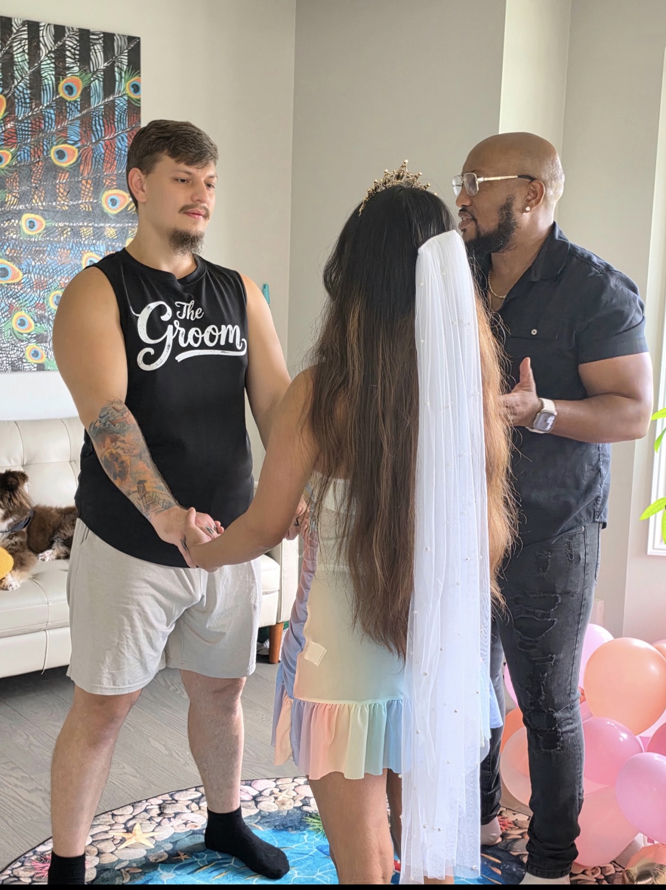 Andrew Alleyne officiating an intimate living-room ceremony for a couple, balloons and family dog nearby