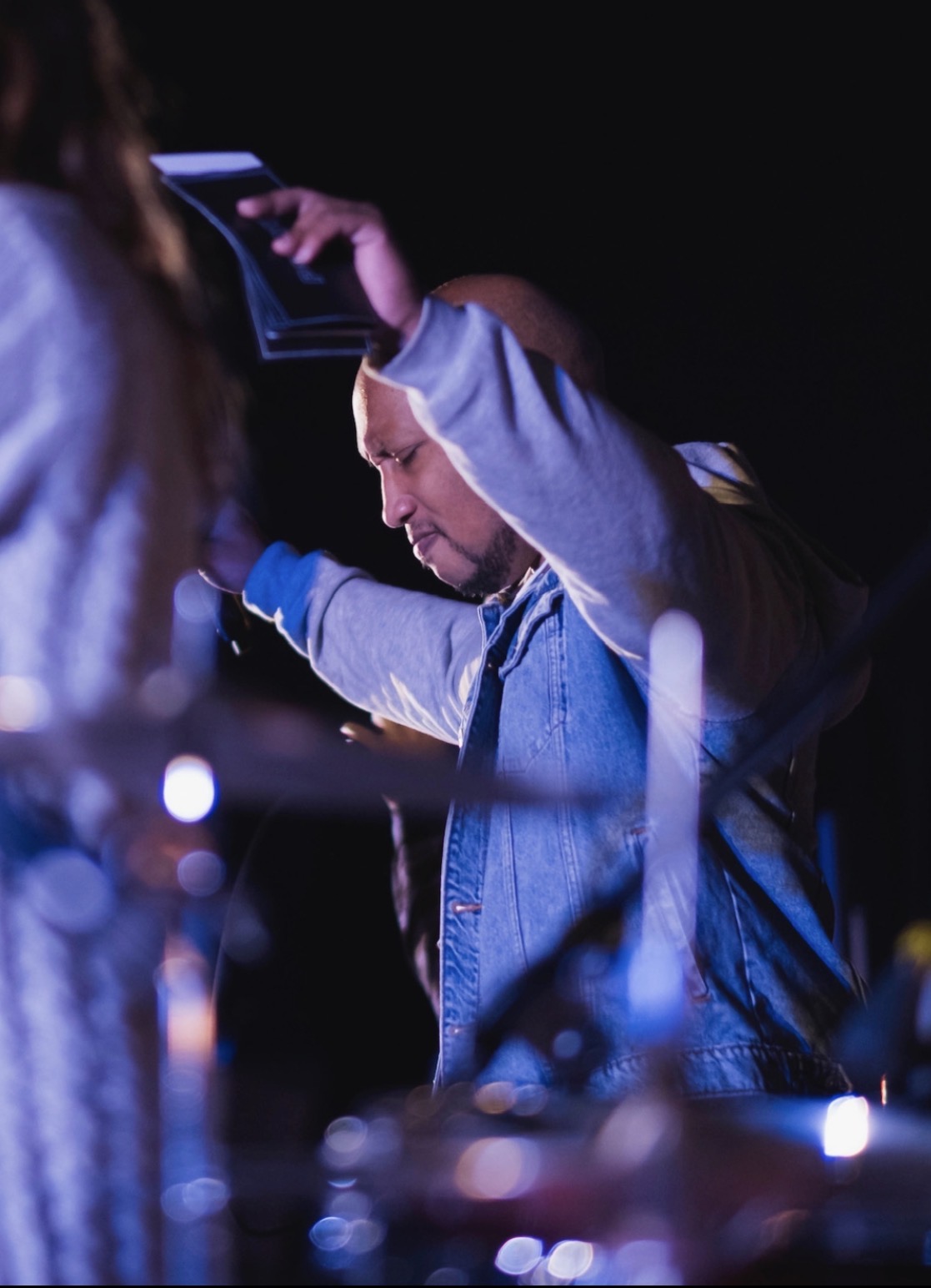 Andrew Alleyne praying with someone at the front of a dimly lit room
