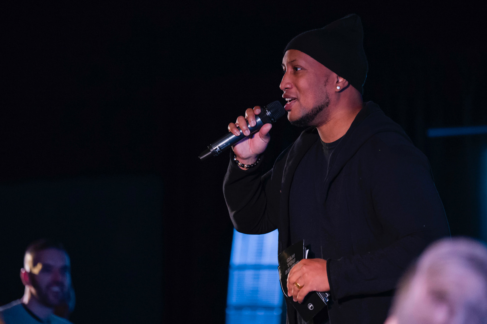 Andrew Alleyne preaching with a microphone under stage lights
