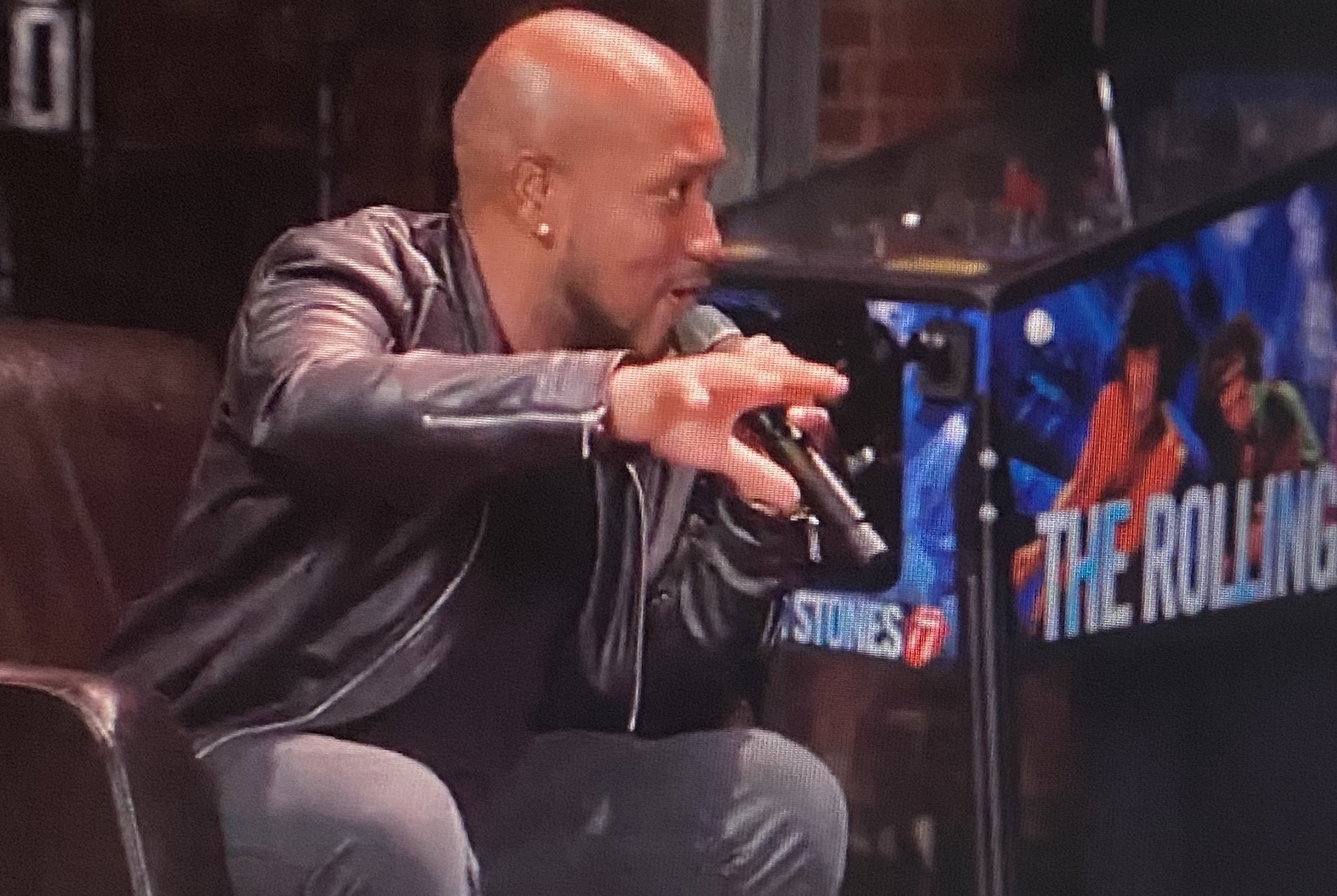 Andrew Alleyne speaking with a microphone while seated in a relaxed setting