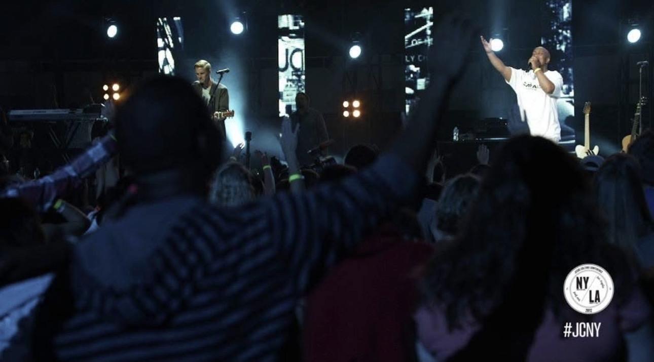 A crowd with hands raised in worship as Andrew Alleyne leads from the stage